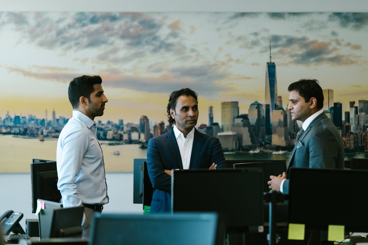 Three businessmen in a meeting with a city skyline background, representing corporate discussion.